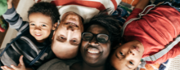 happy family of four laying on ground looking up at camera