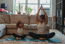 Mom and daughter sitting on yoga mats doing yoga pose together